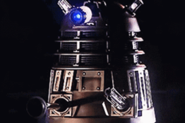 A black Dalek fires and shouts EXTERMINATE!
