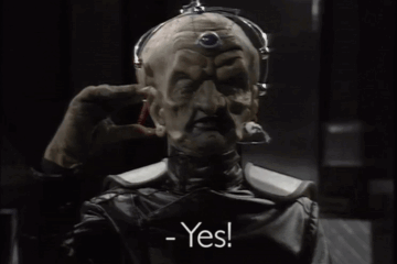 Davros, hand raised, saying YES!