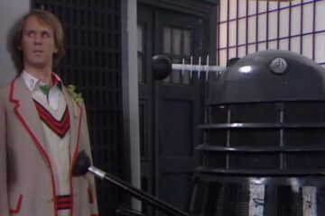 The Fifth Doctor being held at sucker point by a Dalek